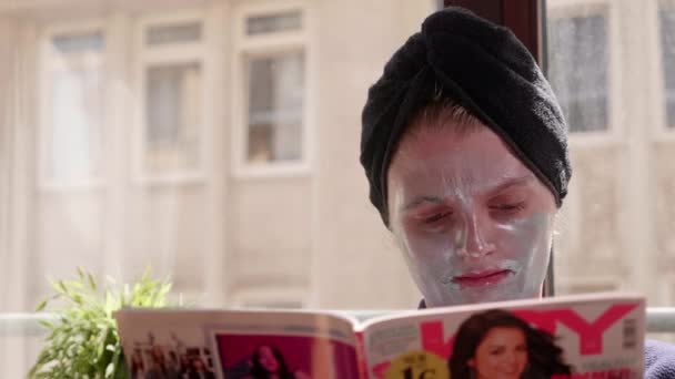 Κορίτσι Μπλε Μάσκα Προσώπου Διαβάζει Ένα Περιοδικό Μόδας — Αρχείο Βίντεο