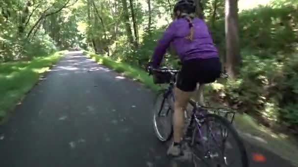 低角度紧跟在一个骑山地自行车的成熟女人后面 骑着自行车沿着一条铺好的铁路在森林里走着 — 图库视频影像