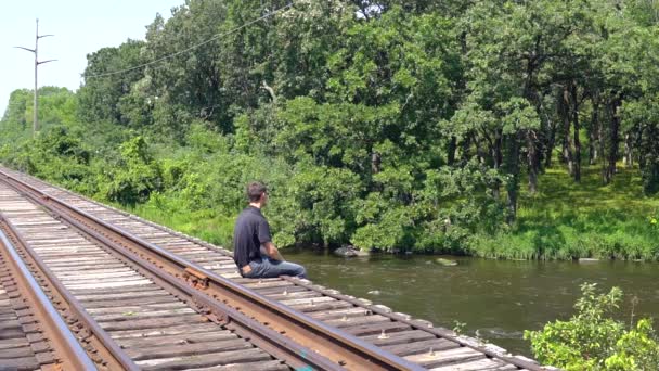Чоловік Сидячи Сільському Поїзді Кидає Каміння Швидку Рухому Річку Внизу — стокове відео