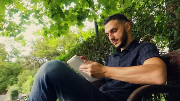 Joven Árabe Europeo Tocando Una Pantalla Tablet Parque — Vídeo de stock