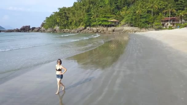 飞机上的一个女人抬头看着摄像机 镜头绕着她在一个荒凉的热带沙滩上散步 — 图库视频影像