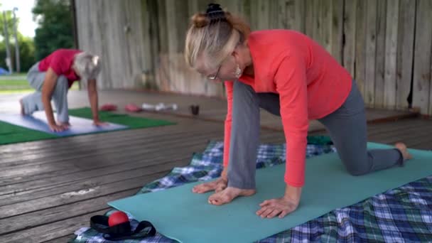 Två Mogna Kvinnor Som Gör Lunge Yoga Pose Och Sträcker — Stockvideo