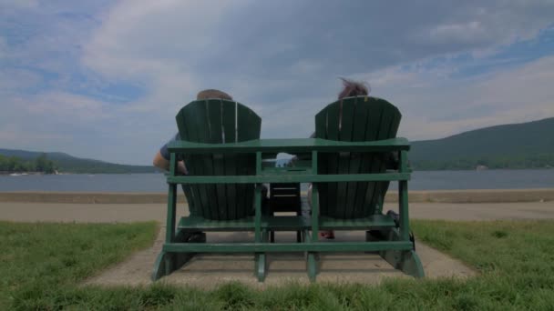 Két Ember Zöld Adirondack Székeken Nézik Tavat Életről Beszélnek — Stock videók