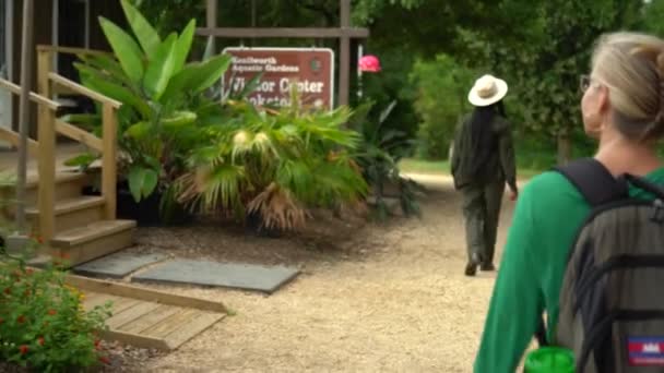 Hübsche Blonde Frau Geht Schild Für Den Kenilworth Aquatic Gardens — Stockvideo