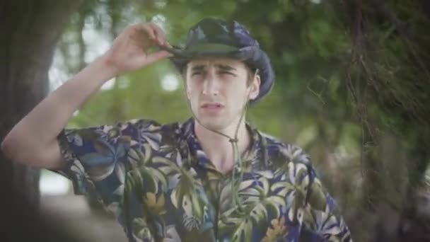 Tilly Hatの若い男性探検家は 熱帯の設定で水平線をスキャンします — ストック動画