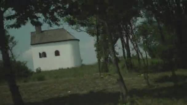 Aufnahme Einer Weißen Kapelle Hinter Bäumen Aus Einem Auto — Stockvideo
