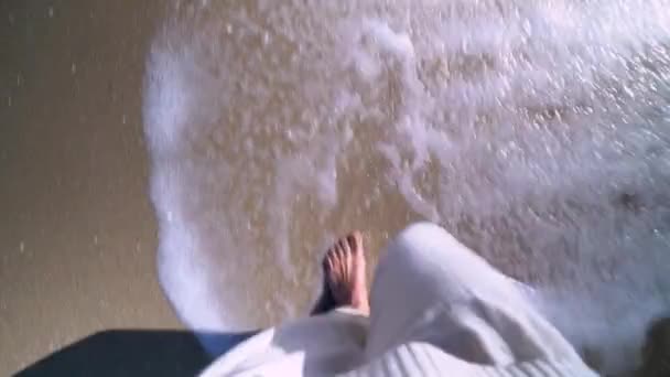 日没時に海岸線に沿って歩く白いドレスを持つ女性の足のPov — ストック動画