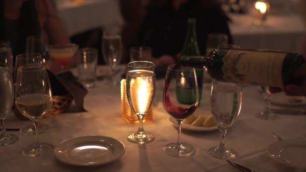 ワインは 素晴らしいダイニングレストランで大きなラウンドでよく装飾されたテーブルに注がれています 女はワインのグラスを口に持ってくる — ストック動画