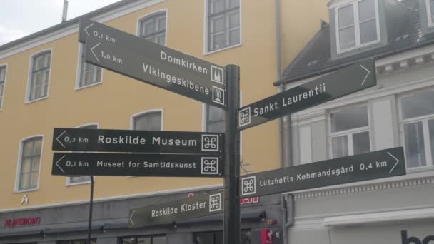 Slow motion tripod shot of signs pointing towards famous attractions in the historical city of Roskilde, Denmark