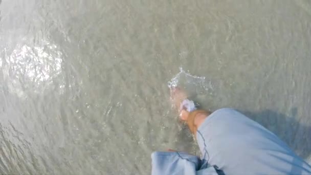 灰色の男のスローモーションビューでは 澄んで涼しい海に歩いてトランクを泳ぐ 彼らは柔らかい砂の上を歩く澄んだ水にスプラッシュとして彼の足のビューを閉じます — ストック動画