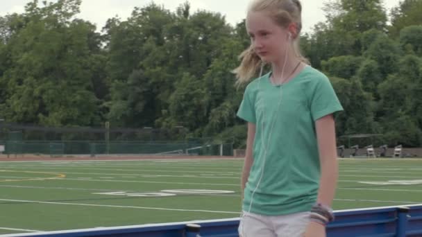 ティーン女の子選手ウォーキングザトラックで高校静かに笑顔に自分自身 — ストック動画