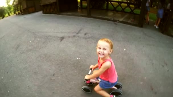 holčička se směje a jezdí na růžovém dětském kole ve zpomalení