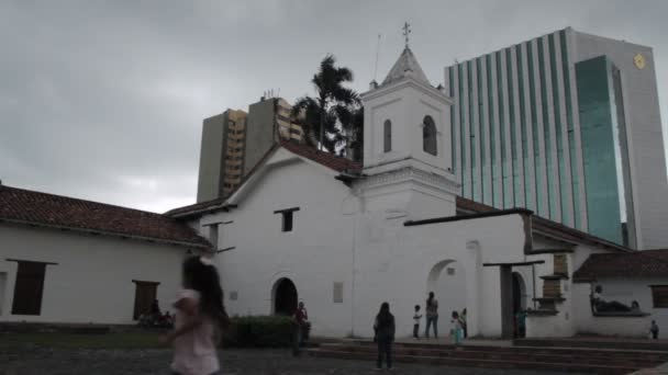 哥伦比亚卡利市 一名儿童在摄像机前奔跑 人们聚集在被建筑物包围的拉默尔教堂前 — 图库视频影像