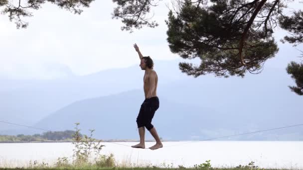 ノルウェー ヨーロッパのスラックラインでバランスをとる男 湖で日当たりの良い明るい日に自然の中で — ストック動画