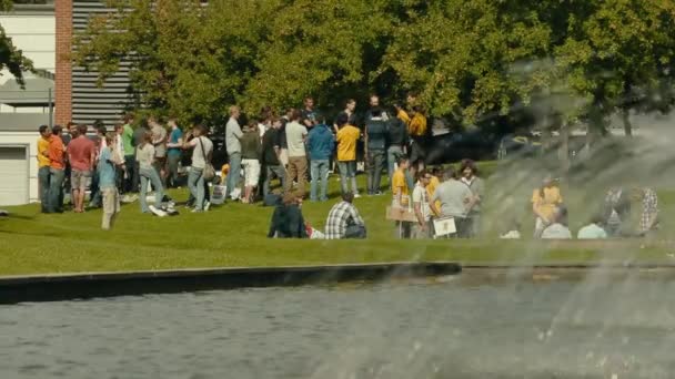 Een Fontein Spuit Voorgrond Als Studenten Genieten Van Een Buitenbijeenkomst — Stockvideo