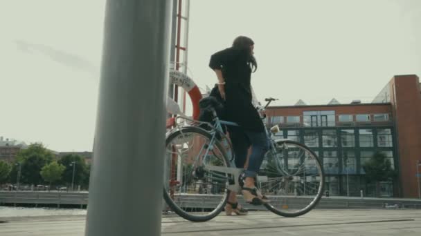 一个骑自行车的年轻女人调整好背包就骑走了 查尔默大学的大楼就在后面 学生骑自行车上下班 — 图库视频影像