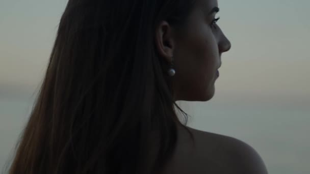 女孩从后面望着大海 在夕阳的背景下 是一座城市 — 图库视频影像