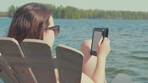 Mujer Joven Relajándose Leyendo Una Silla Adirondack Muelle Con Lago — Vídeos de Stock