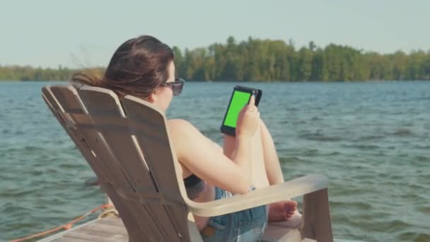 Mujer Joven Relaja Una Silla Adirondack Muelle Junto Lago Verano — Vídeos de Stock