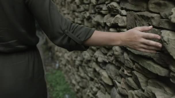 Una Mujer Camina Por Muro Piedra Una Ciudad Arrastrando Mano — Vídeos de Stock