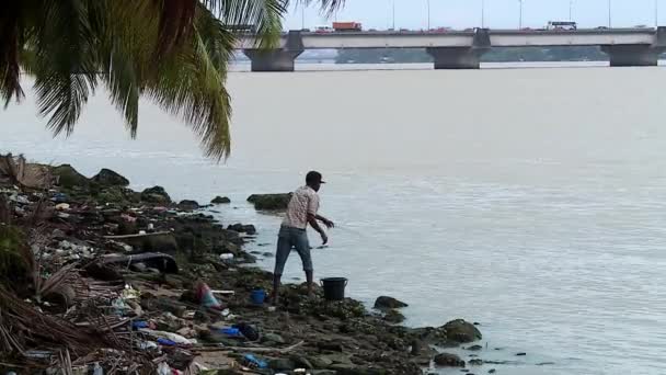 在Charlesde Gaulle桥前面的阿比让肮脏和受污染的泻湖中的年轻渔民 — 图库视频影像