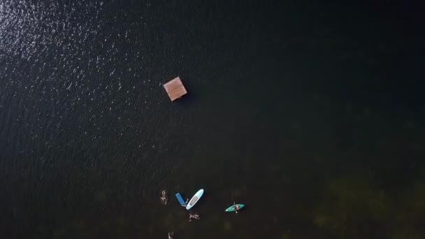 人が泳いだり カヤックをしたり 浮遊ドックで穏やかな湖で遊んだりするドローンの空の鳥の目 — ストック動画