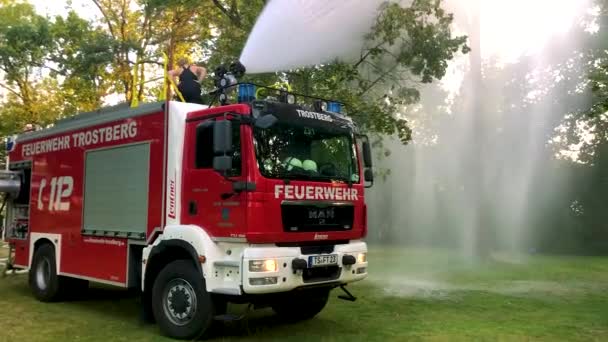 Deutsches Feuerwehrauto Versprüht Wasser Für Kinder Und Bäume Einem Heißen — Stockvideo