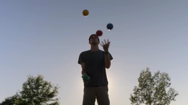 Man Juggling Τέσσερις Μεγάλες Και Πολύχρωμες Μπάλες Στο Ηλιοβασίλεμα — Αρχείο Βίντεο