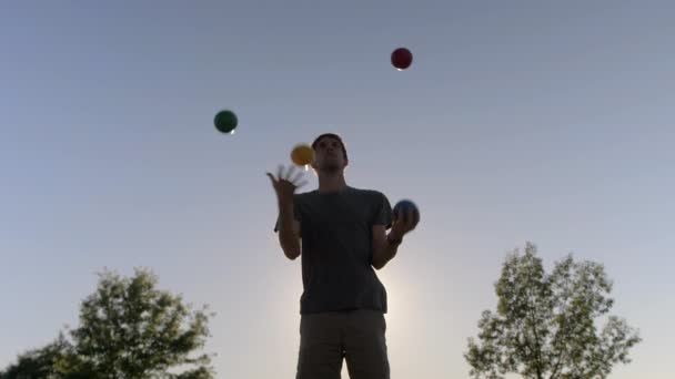 Man Juggling Τέσσερις Μεγάλες Και Πολύχρωμες Μπάλες Στήλες Στο Ηλιοβασίλεμα — Αρχείο Βίντεο