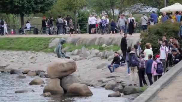 デンマークのコペンハーゲンにあるLangelinieの小さなマーメイドの像の周りに立って座っている人々 — ストック動画