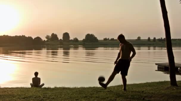 男人在湖边玩足球 — 图库视频影像