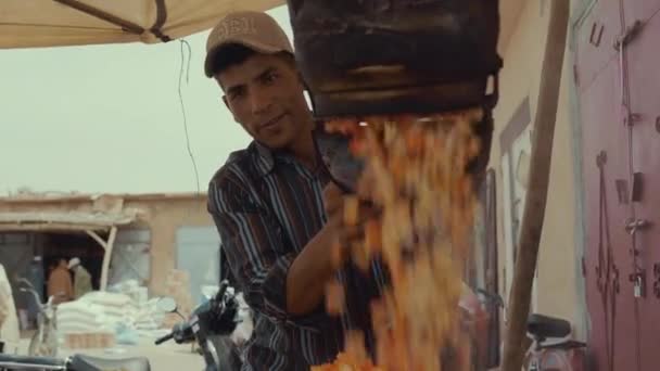 一个摩洛哥男人把一壶热砂糖包裹的爆米花倒入另一个容器 后面是驴子 — 图库视频影像
