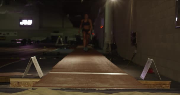 一个女运动员在训练场内跳向摄像机的电影拍摄 沙子盖住镜头 — 图库视频影像