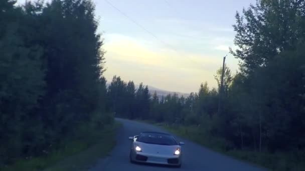 Egy Lamborghini Lehajt Egy Kanyargós Országúton Alkonyatkor Felvillanó Jelzéssel — Stock videók