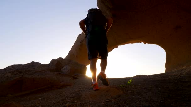 一个背包客走在Tenerife 的一个天然石拱前 在晨光和镜头耀斑中 Hd缩放放大版本 慢动作 — 图库视频影像