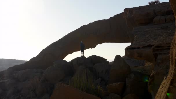 Backpacker Άνθρωπος Στέκεται Πάνω Στους Βράχους Μια Φυσική Πέτρινη Αψίδα — Αρχείο Βίντεο