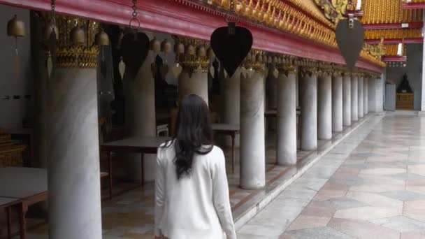 A woman walking along the holy bells at a temple in Bangkok, Thailand