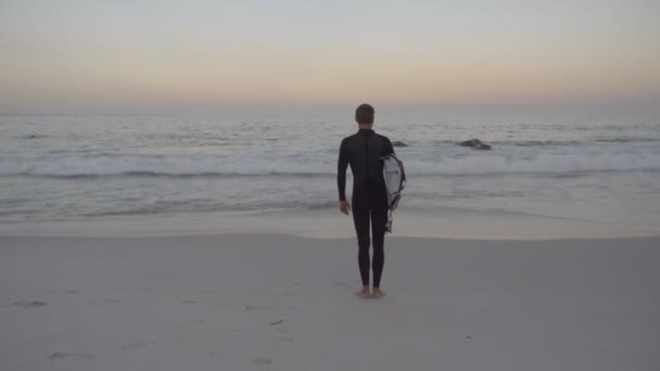 Surfer Piedi Sulla Spiaggia All Alba Tenendo Tavola Surf Città — Video Stock