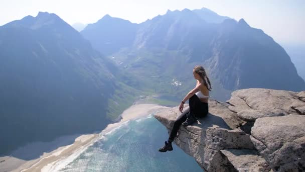 Kadın Dağ Yamacındaki Kayalık Bir Çıkıntıda Otururken Inanılmaz Lofoten Manzarasına — Stok video