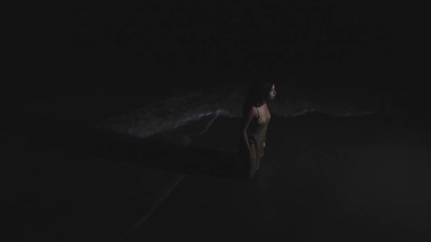 穿着金色衣服坐在膝盖上的非洲裔美国女孩夜间在海滩上失踪的静态镜头 — 图库视频影像