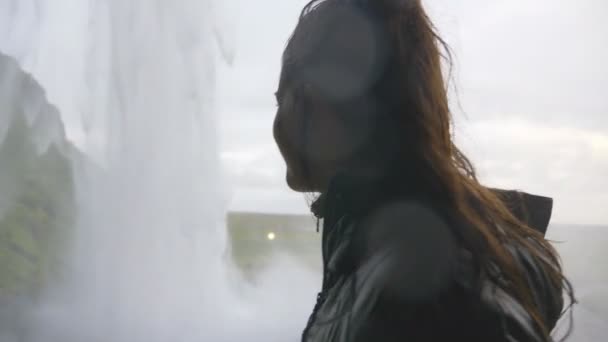 冰岛雄伟瀑布背后的年轻女子好奇欲念 — 图库视频影像