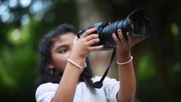 かわいいアジアの女の子がプロの写真家のようにデジタル一眼レフカメラで自然や木の写真を撮っています — ストック動画