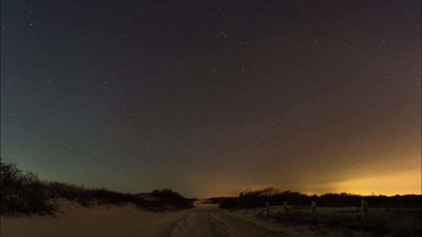 아름다운 밤하늘 언덕으로 둘러싸인 해변의 비포장도로 위에서 회전한다 — 비디오