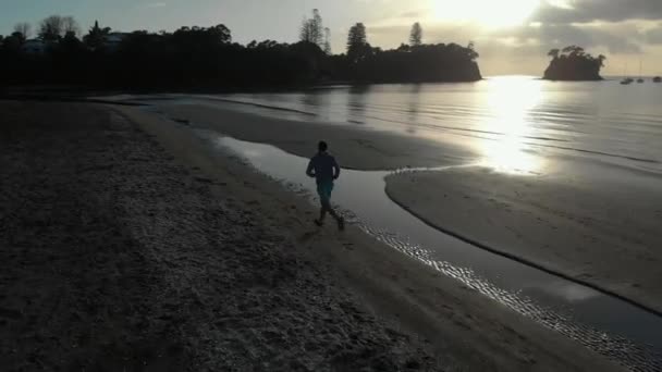 Aerial Follow Shot Silhouetted Young Man Running Beach Auckland Nowa — Wideo stockowe