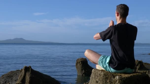 Young Fit Man Mediteren Yoga Poseren Rotsen Het Strand Ochtend — Stockvideo