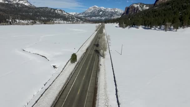 雪に覆われた冬の山の高速道路の隣に空飛ぶドローン — ストック動画