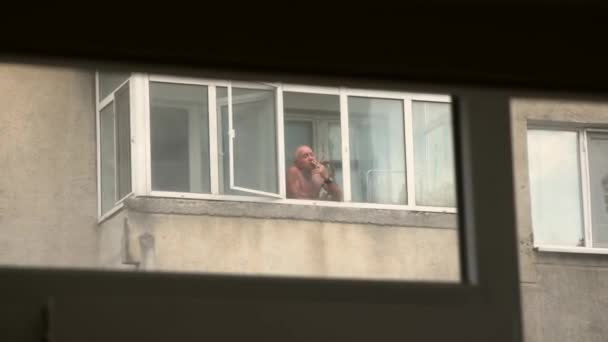 Viejo Hombre Topless Fumando Por Ventana Del Balcón — Vídeo de stock