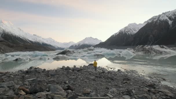 在日落时分的一个寒冷的冬夜 一个女人走到新西兰塔斯曼冰川湖畔的广角镜头 — 图库视频影像