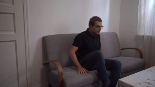 Ung Man Sitter Soffan Och Lägger Smartphone Fickan — Stockvideo