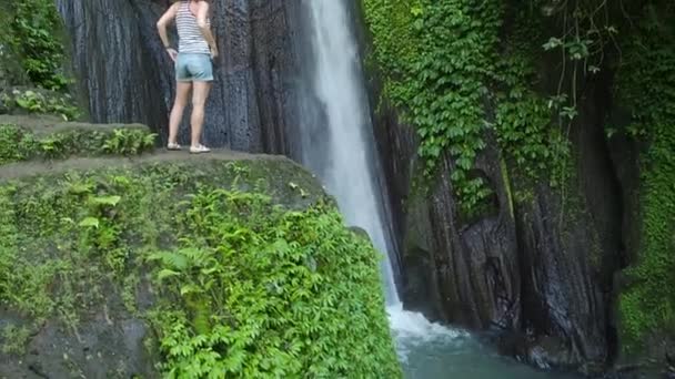 Ein Mädchen Steht Neben Einem Wasserfall Auf Bali Indonesien Zeitlupenvideo — Stockvideo